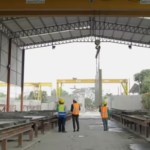 Experienced manufacturing plant manager mentoring a younger supervisor during a floor walkthrough in an industrial facility