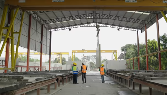 Experienced manufacturing plant manager mentoring a younger supervisor during a floor walkthrough in an industrial facility
