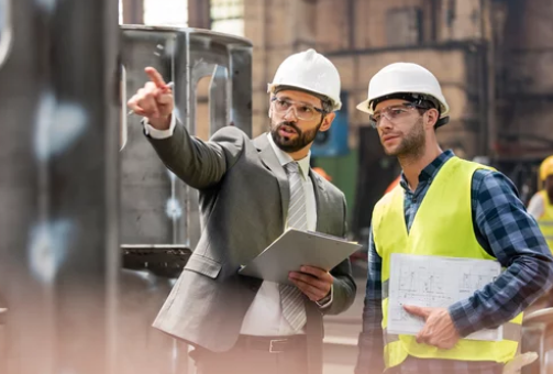 Experienced manufacturing supervisor reviewing production processes with a floor operator in a precast concrete plant