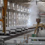 Plant manager and floor supervisor reviewing a problem-solving sprint board next to production equipment in an industrial facility