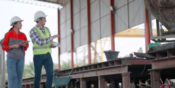Plant supervisor and floor lead reviewing a practical fix at a production workstation in a small manufacturing facility