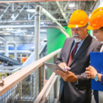 Plant manager reviewing equipment plans on an industrial manufacturing floor